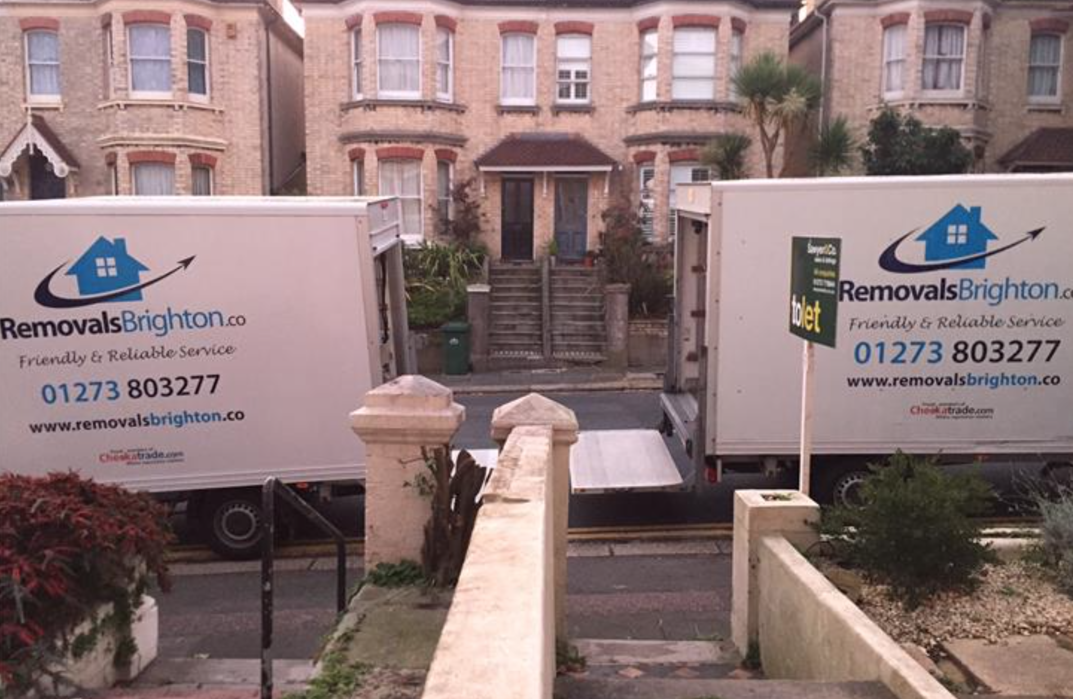 Two Removals Brighton vans parked outside a Victorian house in Brighton